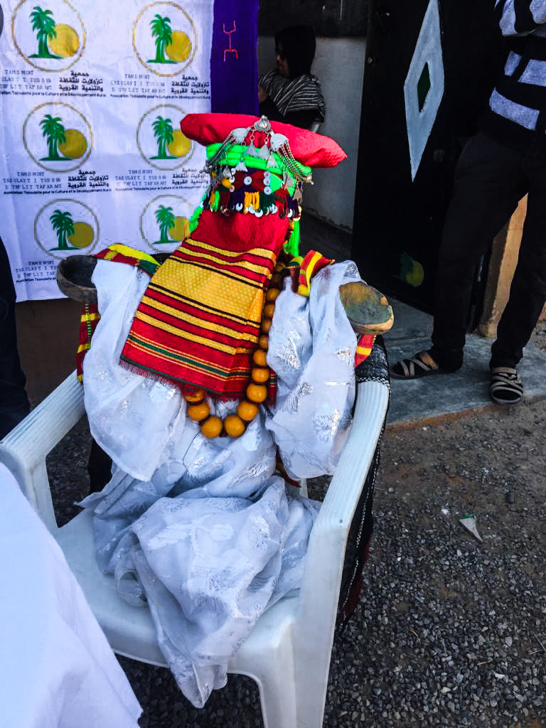 دمية تلغنجا جالسة على كرسي، مكسوّة ومحجّبة كعروس